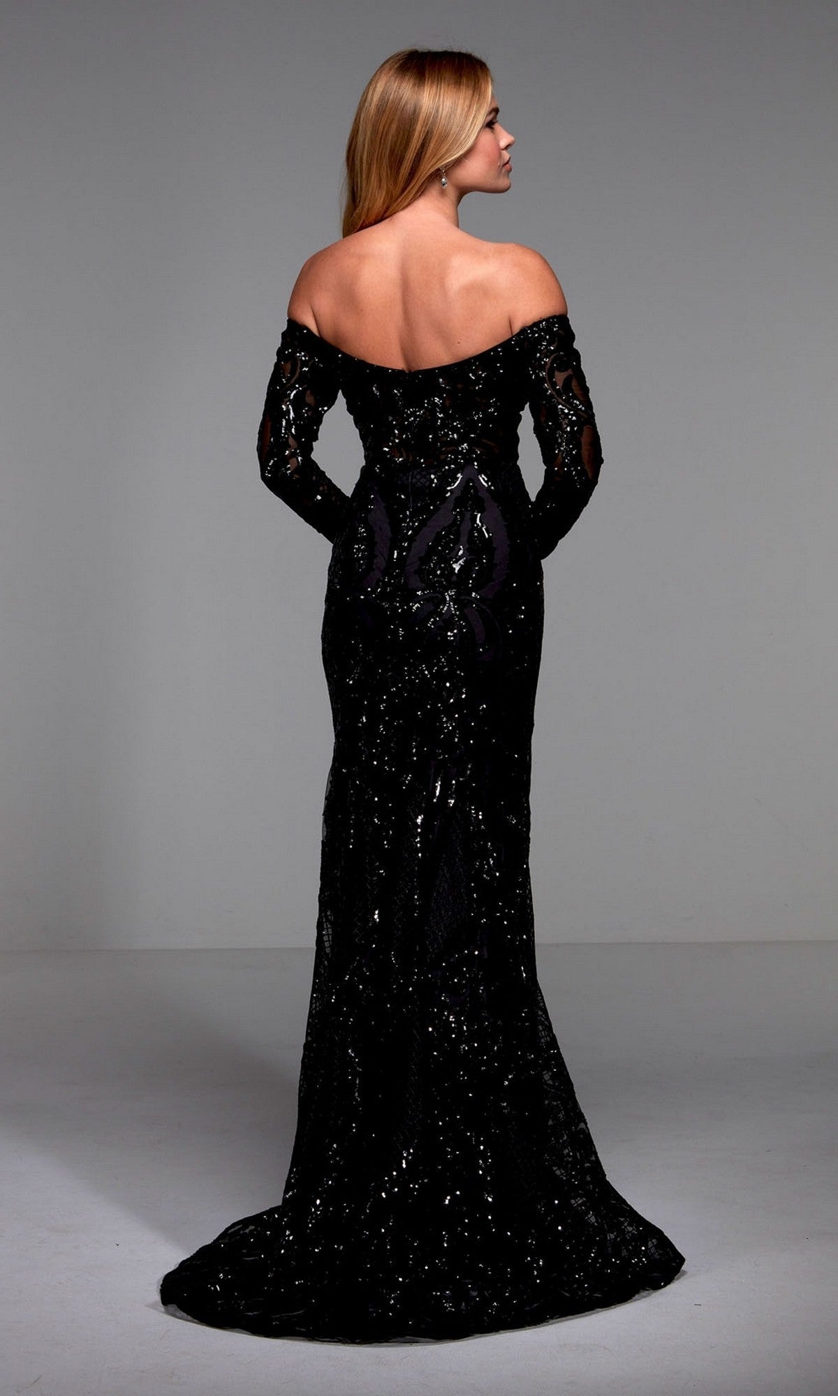 A woman faces away from the camera, showcasing the Alyce 27544—a long black formal dress with off-the-shoulder long sleeves and sparkling sequin details.